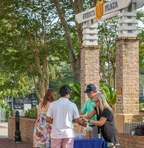 Guests picking up their glasses for Bubbly Baytowne at the entrance of the Village of Baytowne Wharf