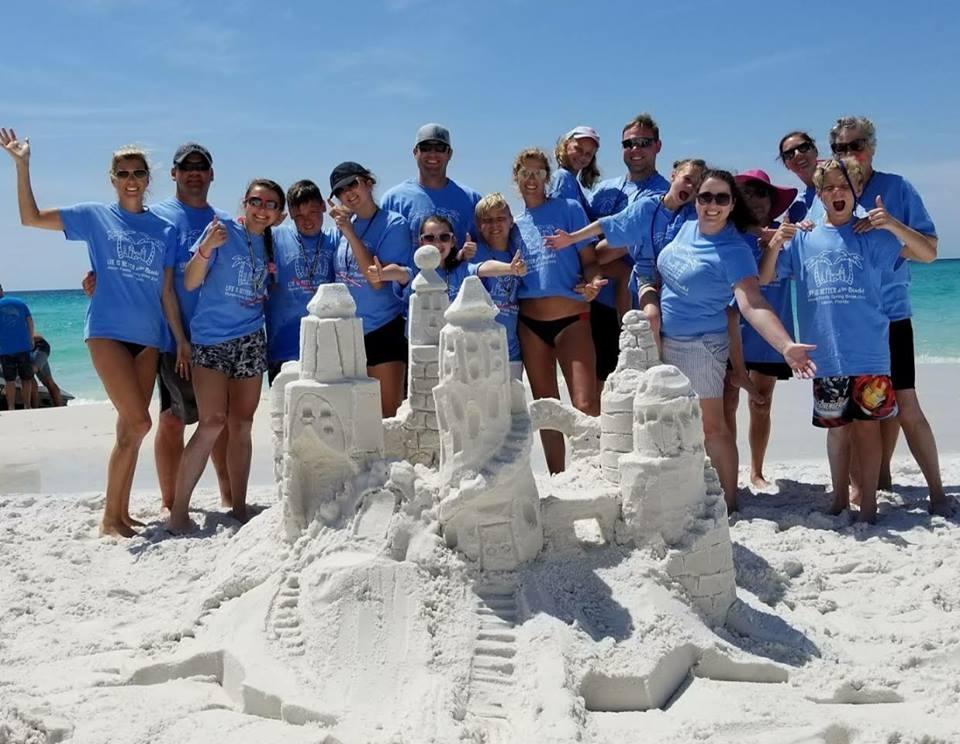 A family posing in front of the sandcastle they built in Destin