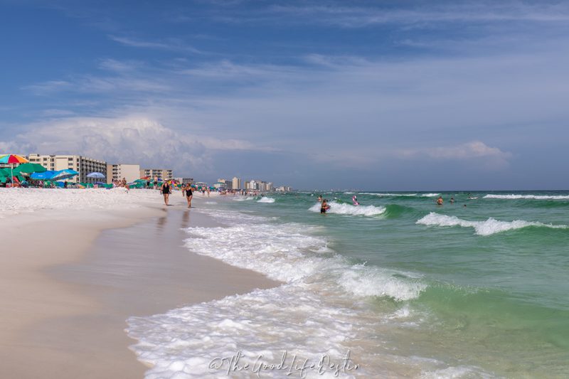 People walking on the beach in Destin. Summer is the best time to visit Destin for warm weather