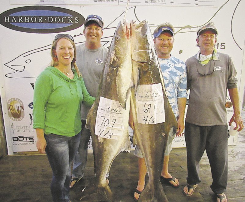 April Cobia Fishing tournament winners posing with a fish at harbor docks in Destin