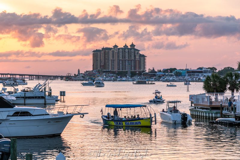 Destin Water Taxi at sunset on Holiday Isle with other boats and Harborwalk Village in the background