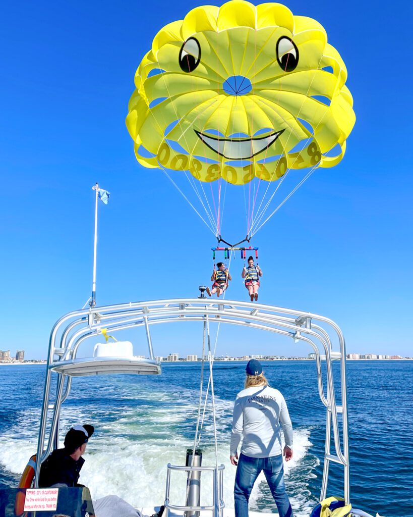 A captain watching as people lift into the air while parasailing in Destin