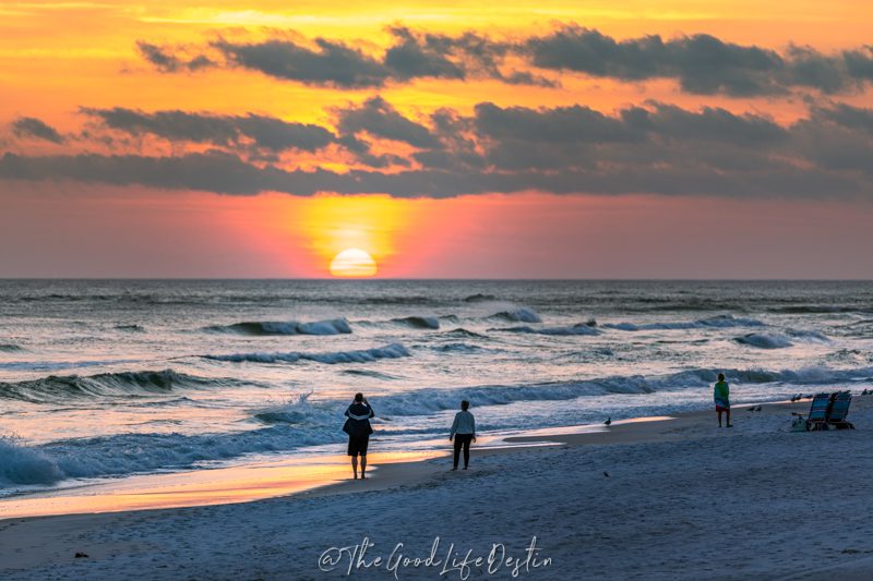 People in Destin watching the sunset over the water in January