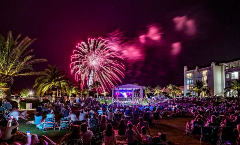 People on the lawn watching the Alys Beach July 4th Fireworks exploding behind the stage