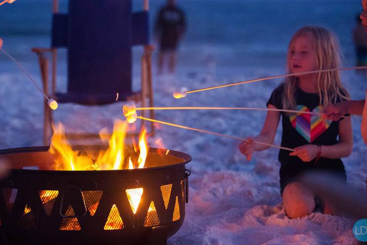 A girl roasting marshmallows in a beach bonfire in Destin