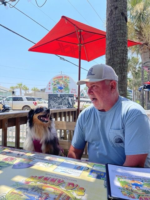 A man and his dog eating at Kenny D's Beach Bar
