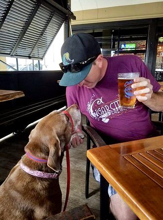 A man enjoying a beer with his dog at the Craft Bar in Destin