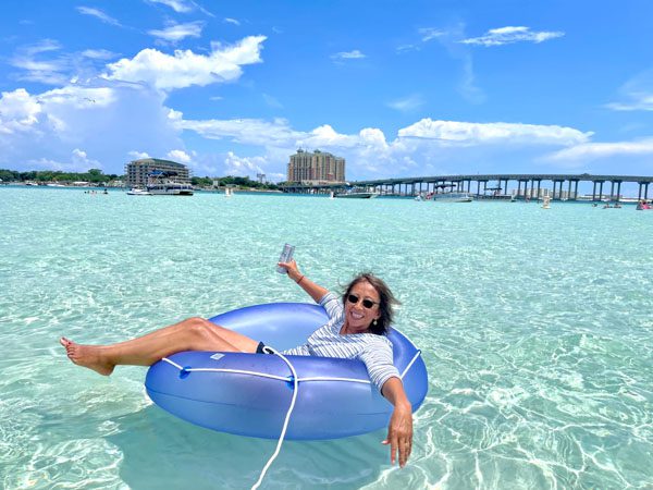 A woman floating in a pool float at Crab Island with sparkling blue clear water