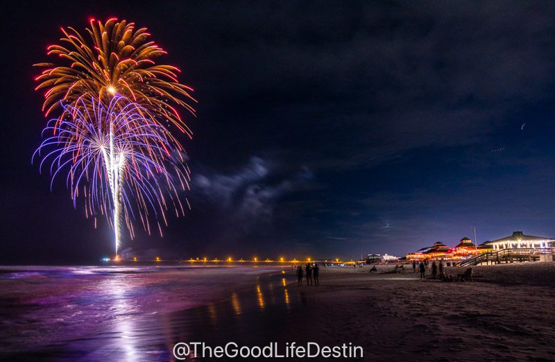 Fireworks at the pier on Okaloosa Island with people watching from the Boardwalk Beach